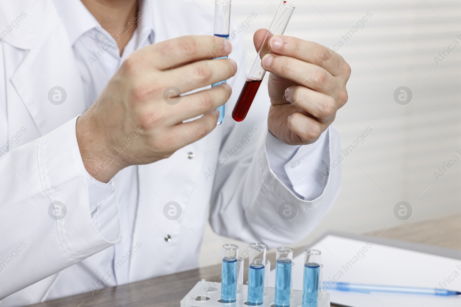 Photo of Scientist with test tubes working in laboratory, closeup