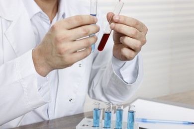 Photo of Scientist with test tubes working in laboratory, closeup