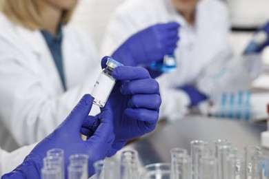 Photo of Scientist with vial working in laboratory, closeup