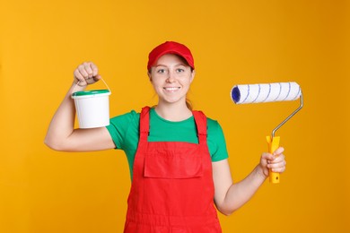 Photo of Professional painter with roller and bucket of paint on orange background