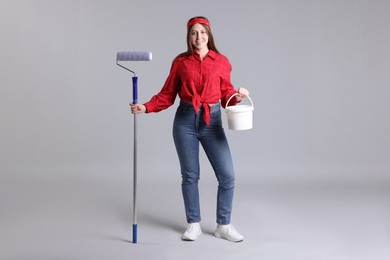 Photo of Woman with roller and bucket of paint on light grey background