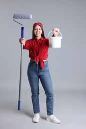 Photo of Woman with roller and bucket of paint on light grey background