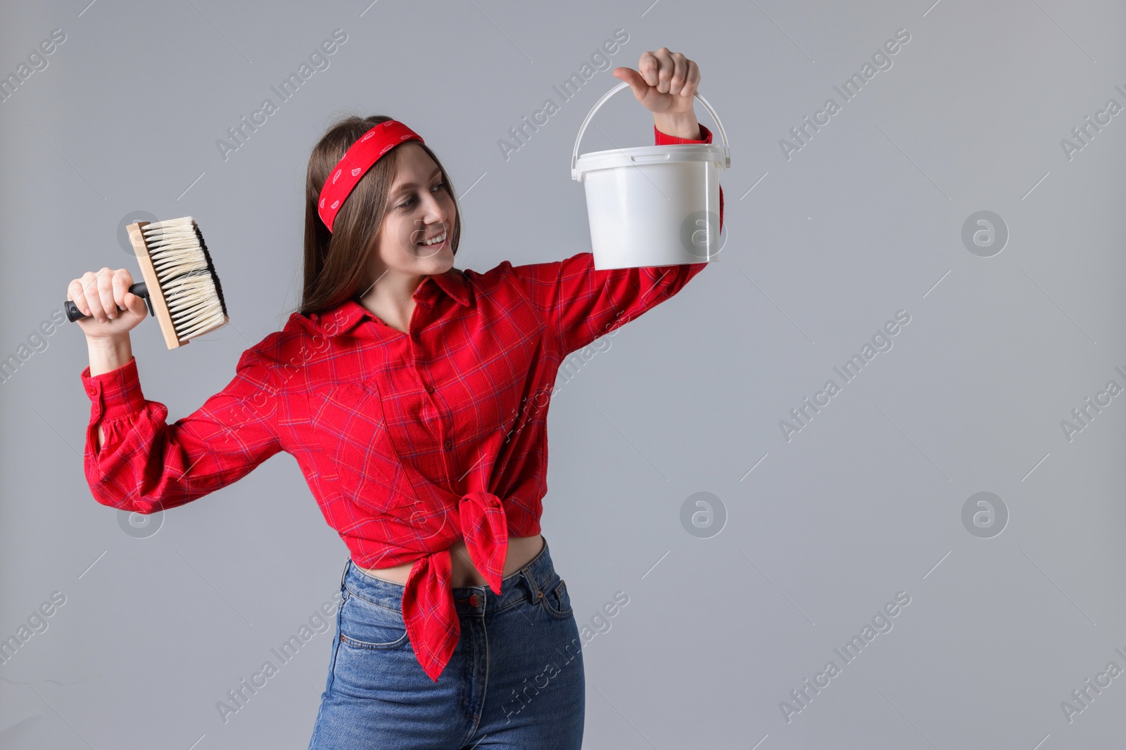 Photo of Woman with brush and bucket of paint on light grey background. Space for text