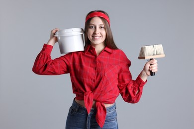 Photo of Woman with brush and bucket of paint on light grey background