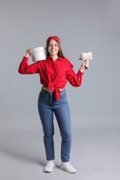 Photo of Woman with brush and bucket of paint on light grey background