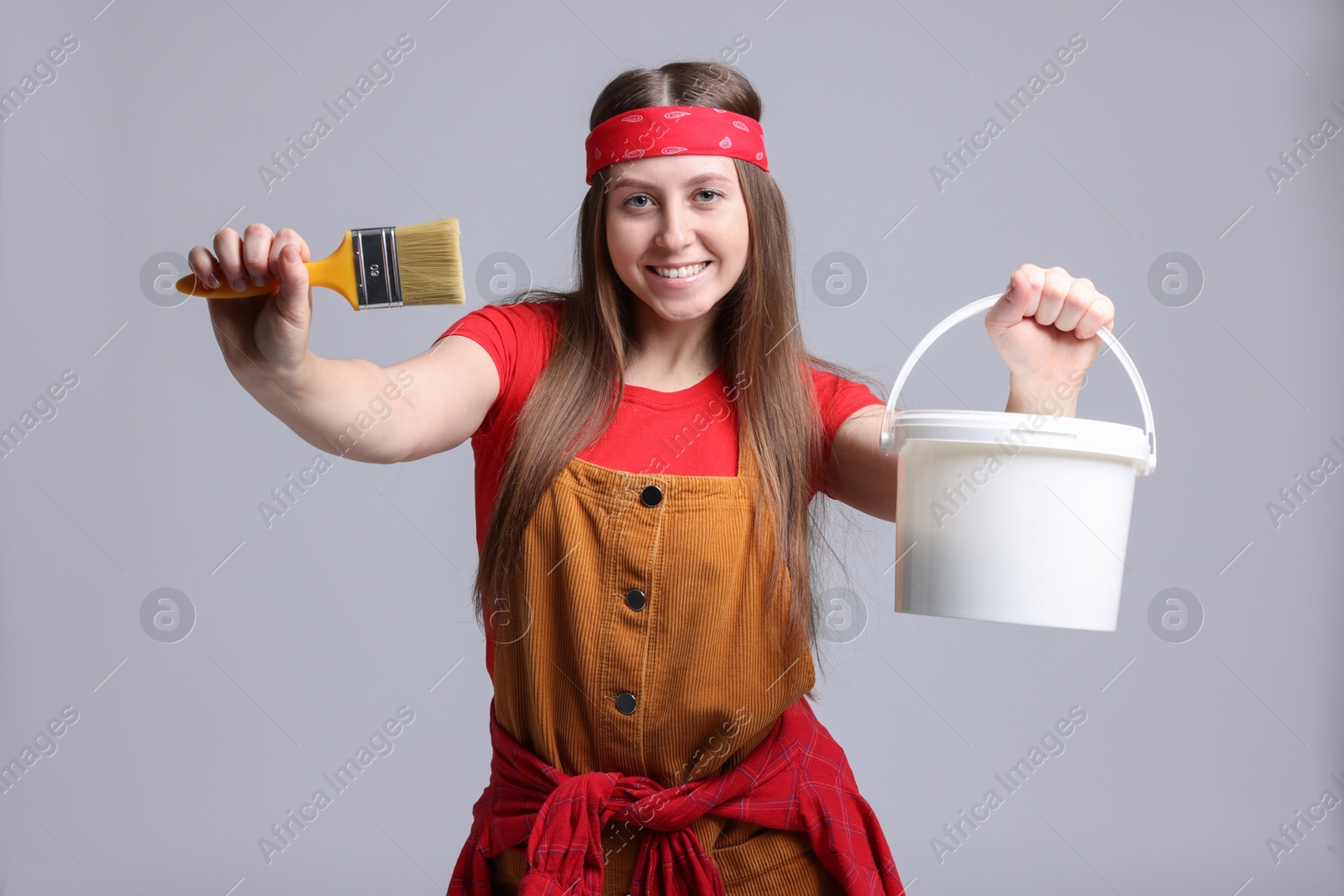 Photo of Woman with brush and bucket of paint on light grey background