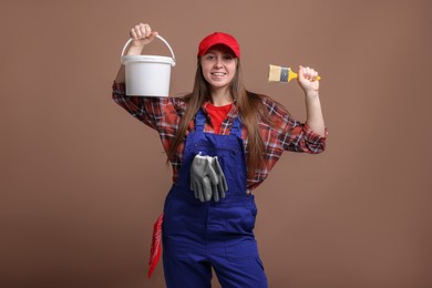 Photo of Professional painter with brush and bucket of paint on brown background