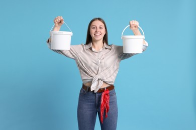 Photo of Woman with buckets of paint on light blue background