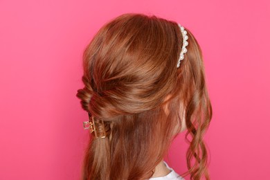 Photo of Teenage girl with stylish hair accessories on pink background, back view