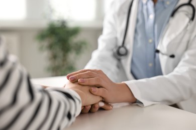 Photo of Doctor supporting patient during appointment in hospital, closeup of hands