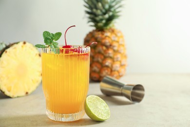 Photo of Tasty pineapple cocktail with mint and cherry in glass served on light table