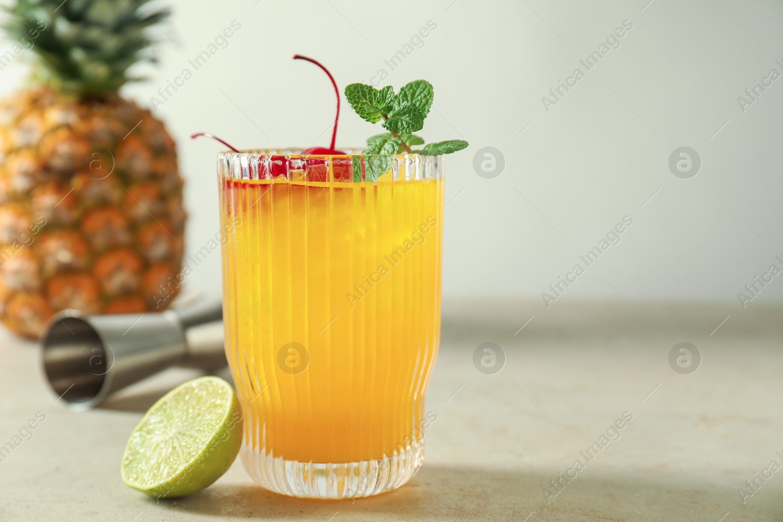 Photo of Tasty pineapple cocktail with mint and cherry in glass served on light table, space for text