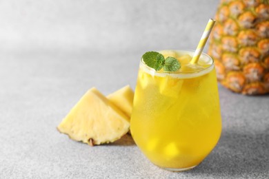 Photo of Tasty pineapple cocktail with mint in glass on gray table