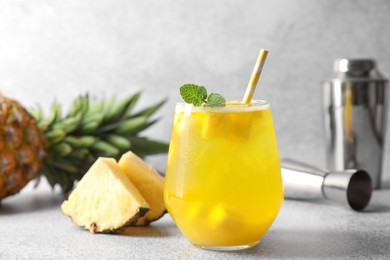 Photo of Tasty pineapple cocktail with mint in glass on gray table