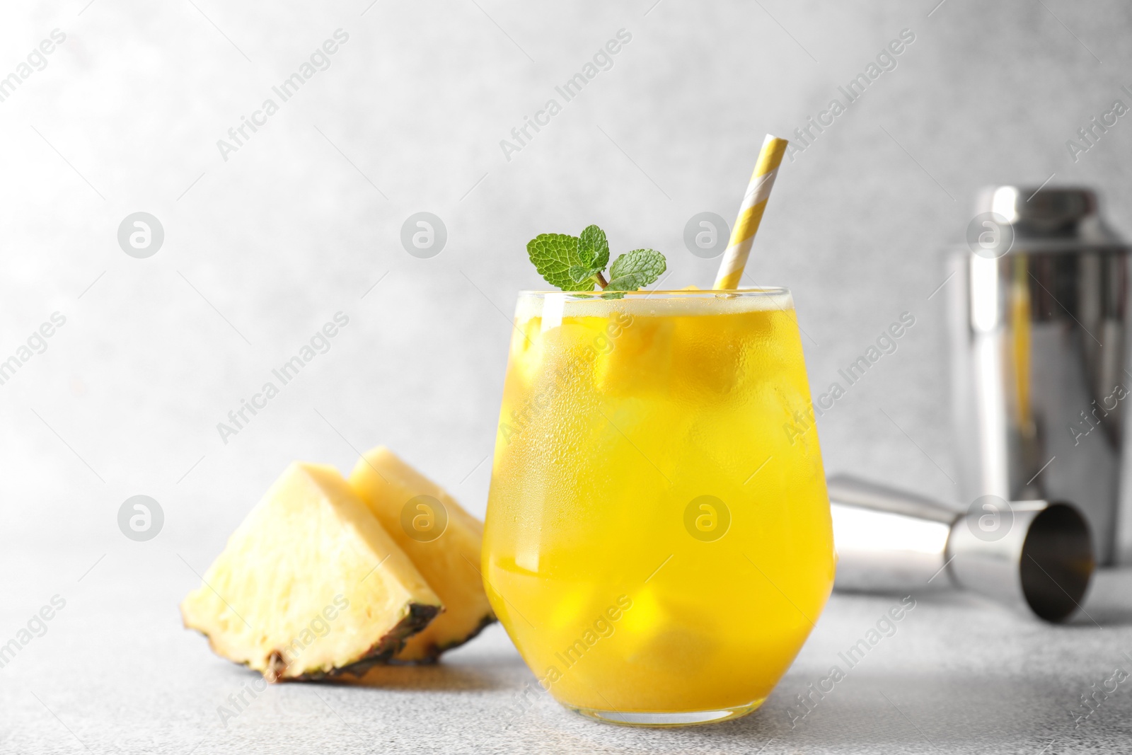 Photo of Tasty pineapple cocktail with mint in glass on gray table