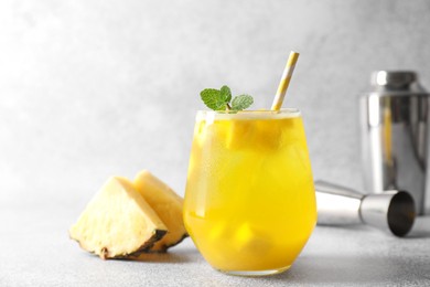 Photo of Tasty pineapple cocktail with mint in glass on gray table