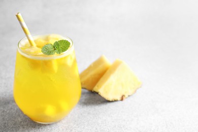 Photo of Tasty pineapple cocktail with mint in glass on gray table, space for text