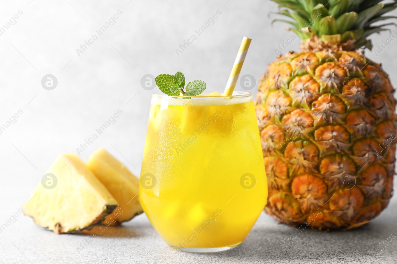 Photo of Tasty pineapple cocktail with mint in glass on gray table