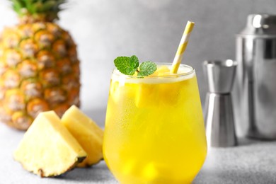 Photo of Tasty pineapple cocktail with mint in glass on gray table, closeup