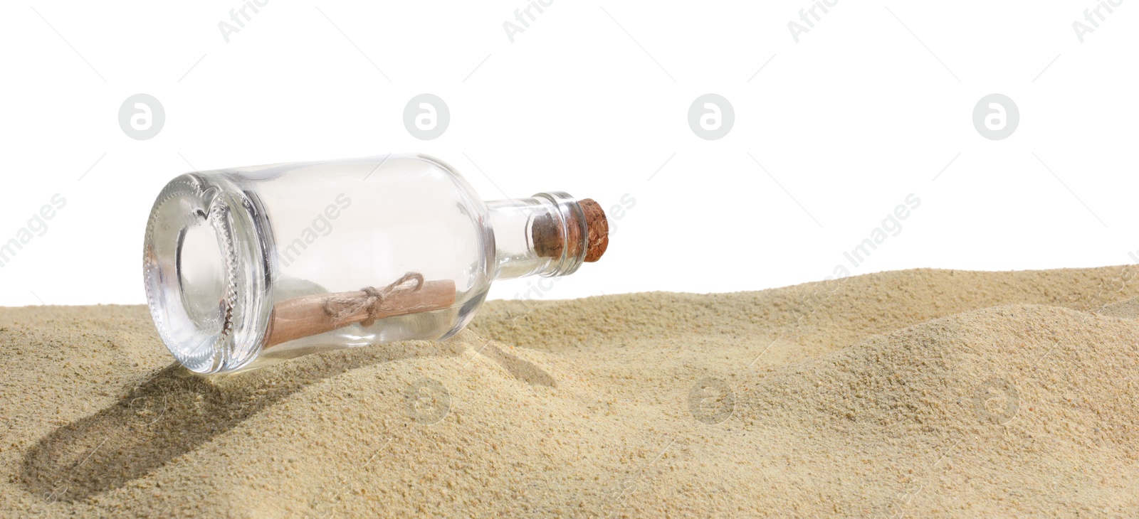 Photo of Rolled letter in corked glass bottle on sand against white background