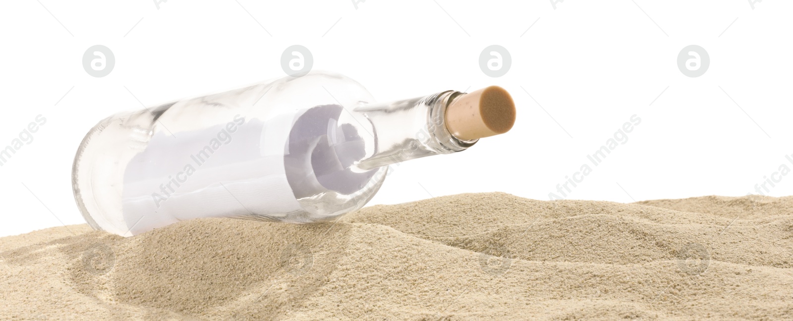 Photo of Rolled letter in corked glass bottle on sand against white background