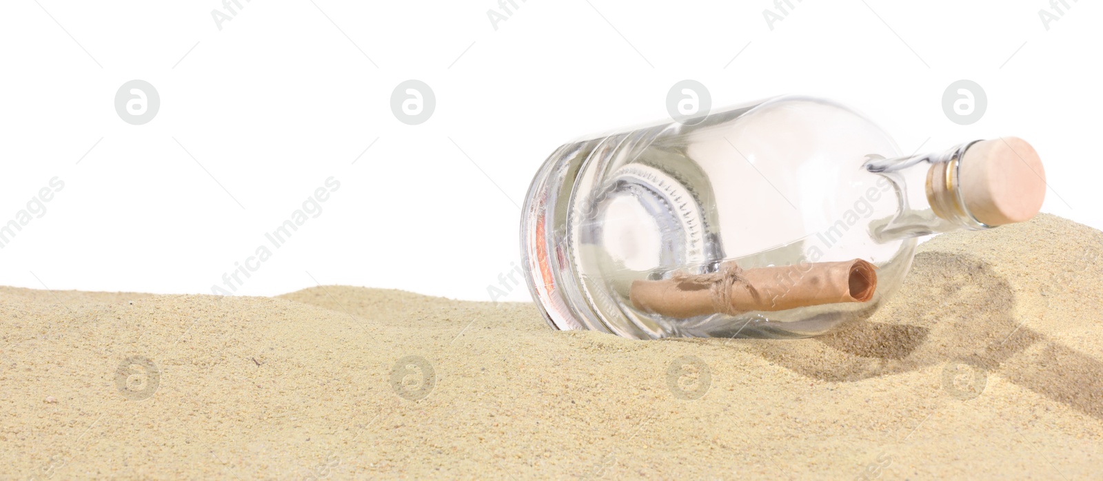 Photo of Rolled letter in corked glass bottle on sand against white background