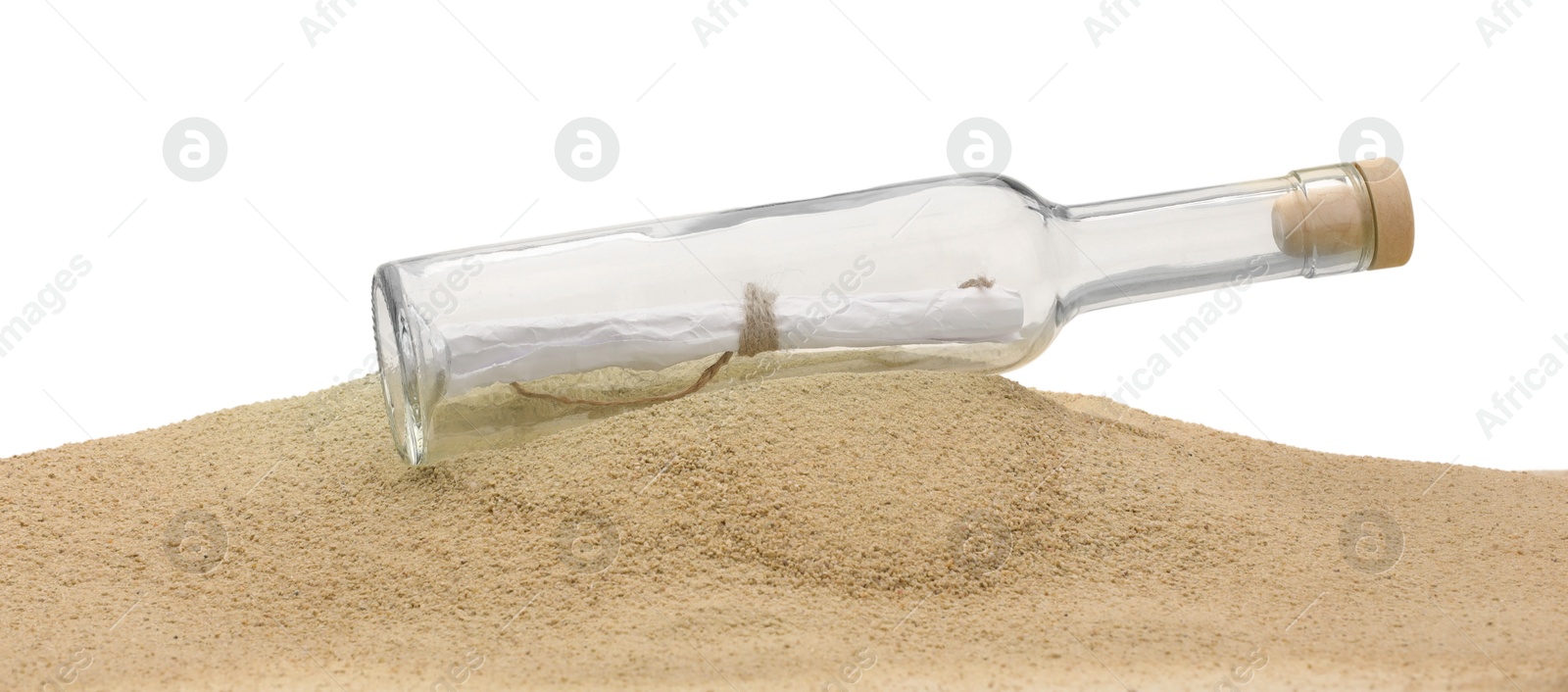 Photo of Rolled letter in corked glass bottle on sand against white background