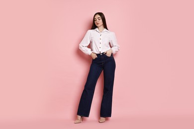 Photo of Beautiful young woman in stylish jeans on pink background