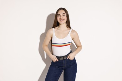 Photo of Smiling woman in stylish jeans on light background