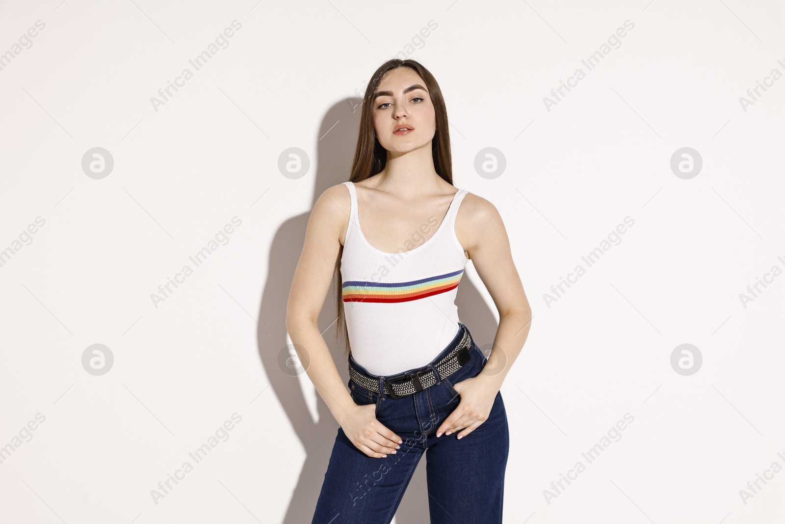 Photo of Beautiful young woman in stylish jeans on light background