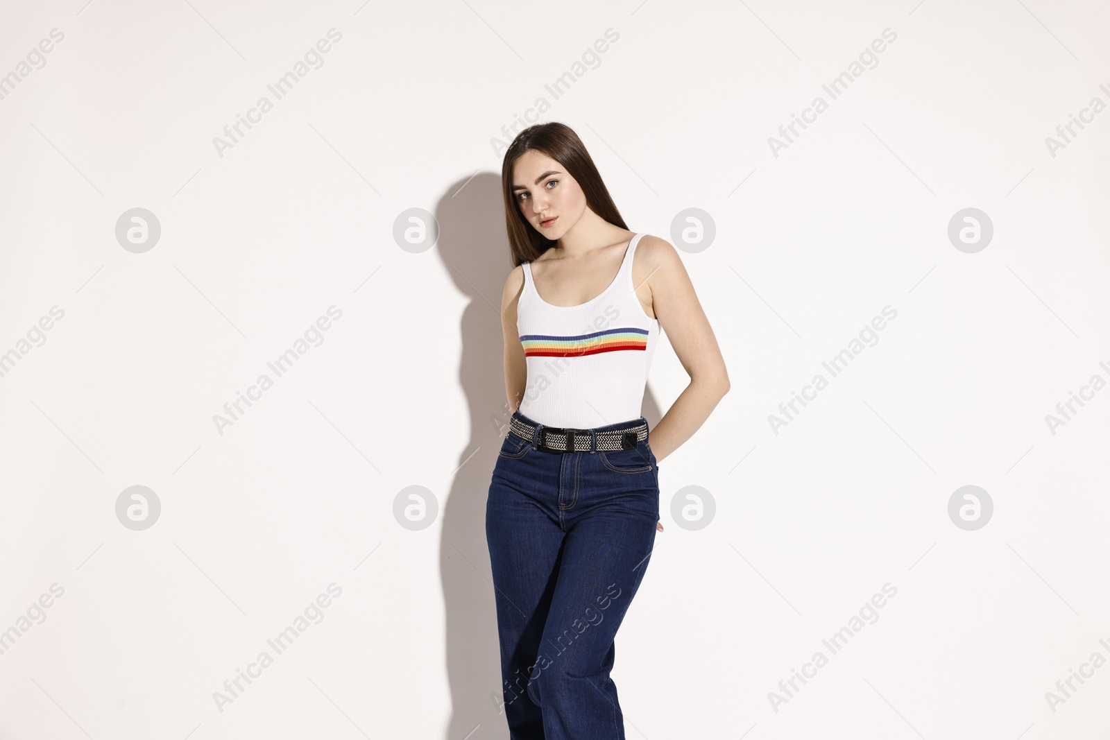 Photo of Beautiful young woman in stylish jeans on light background