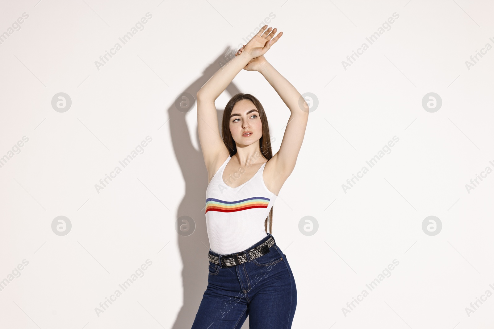 Photo of Beautiful young woman in stylish jeans posing on light background