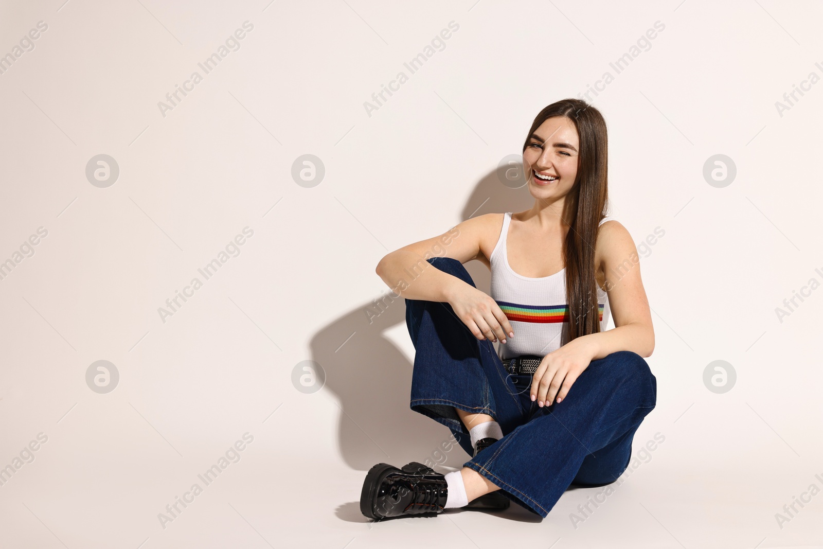 Photo of Happy woman in stylish jeans on light grey background. Space for text