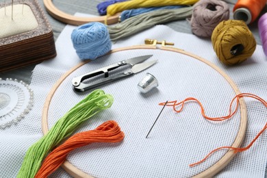 Photo of Different sewing supplies for embroidery on grey wooden table, closeup