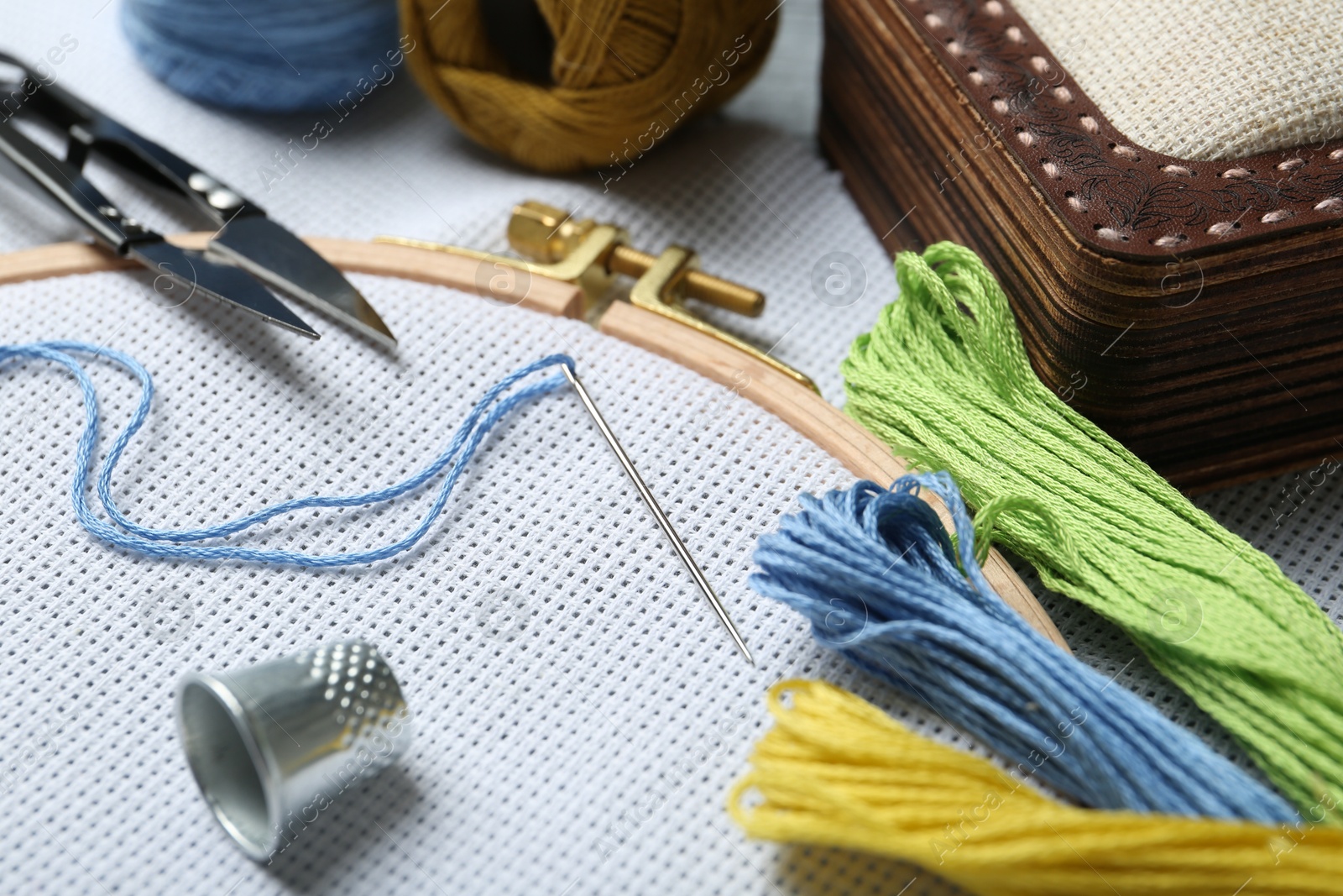 Photo of Different sewing supplies for embroidery on table, closeup