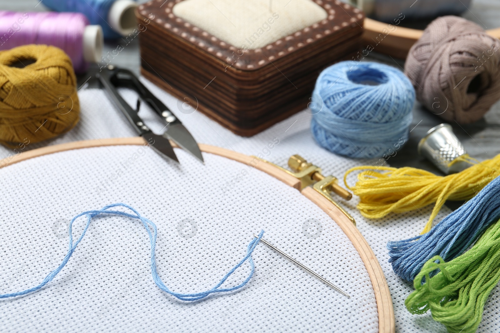 Photo of Different sewing supplies for embroidery on table, closeup