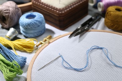 Photo of Different sewing supplies for embroidery on table, closeup