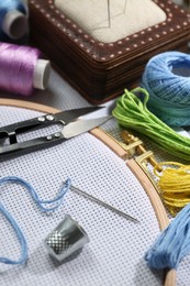 Photo of Different sewing supplies for embroidery on table, closeup