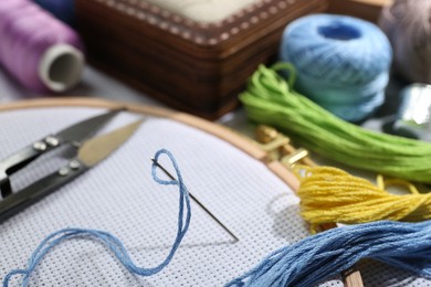 Photo of Different sewing supplies for embroidery on table, closeup