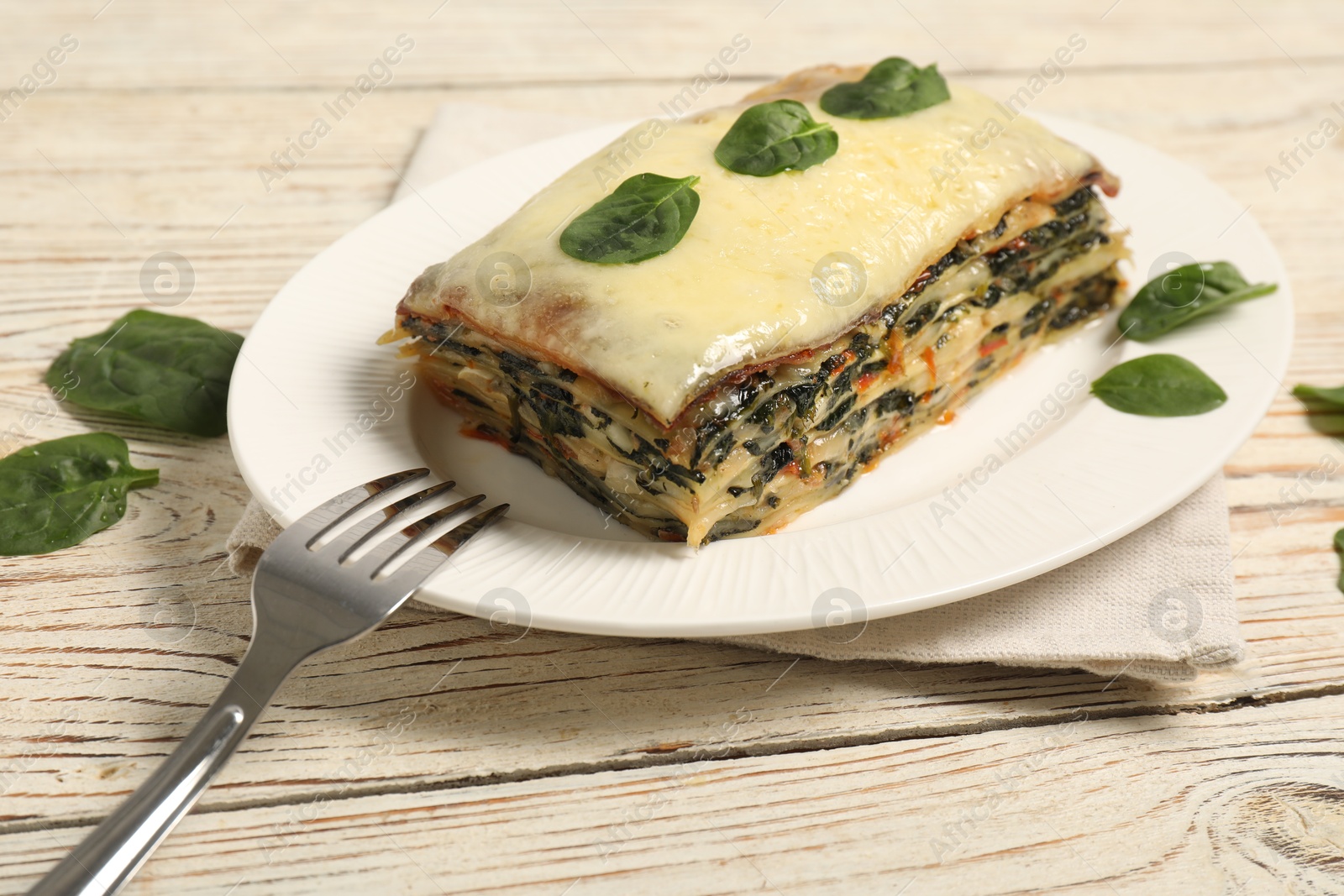 Photo of Piece of tasty spinach lasagna on wooden table, closeup