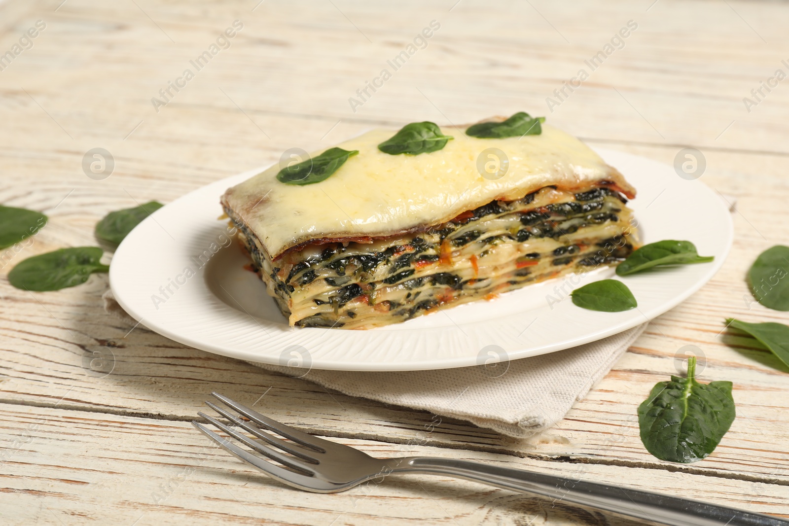 Photo of Piece of tasty spinach lasagna on wooden table, closeup