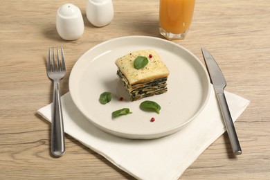 Photo of Piece of tasty spinach lasagna served on wooden table