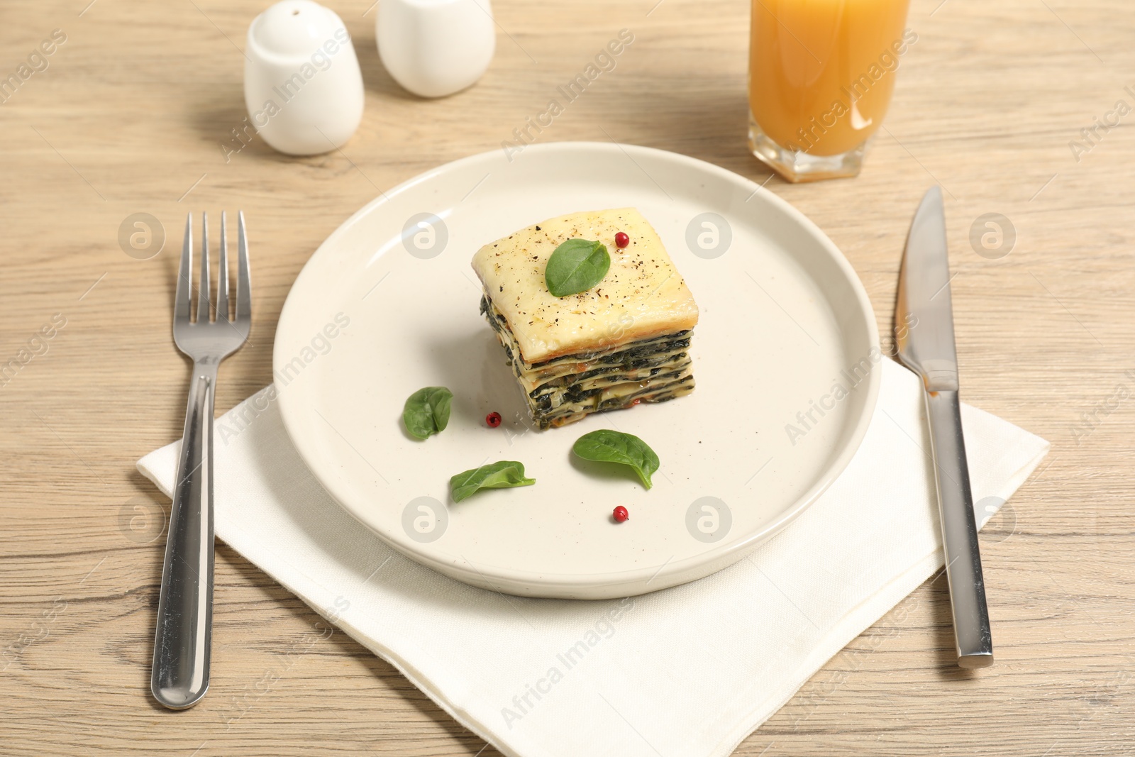 Photo of Piece of tasty spinach lasagna served on wooden table