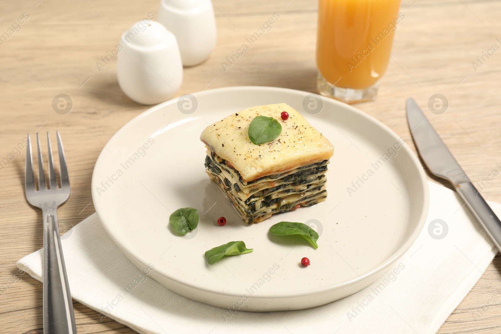 Photo of Piece of tasty spinach lasagna served on wooden table, closeup