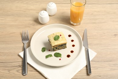 Photo of Piece of tasty spinach lasagna served on wooden table