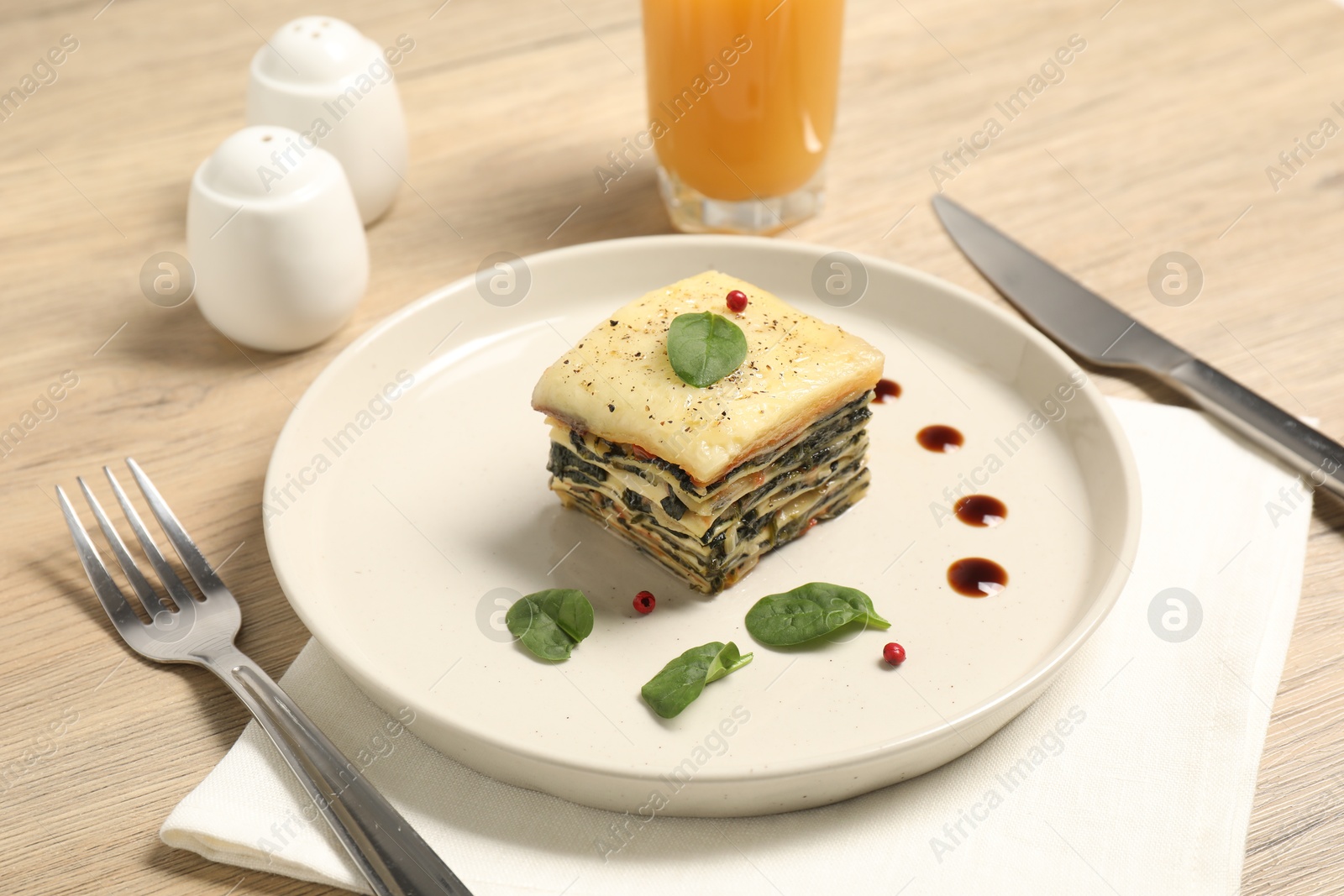 Photo of Piece of tasty spinach lasagna served on wooden table, closeup