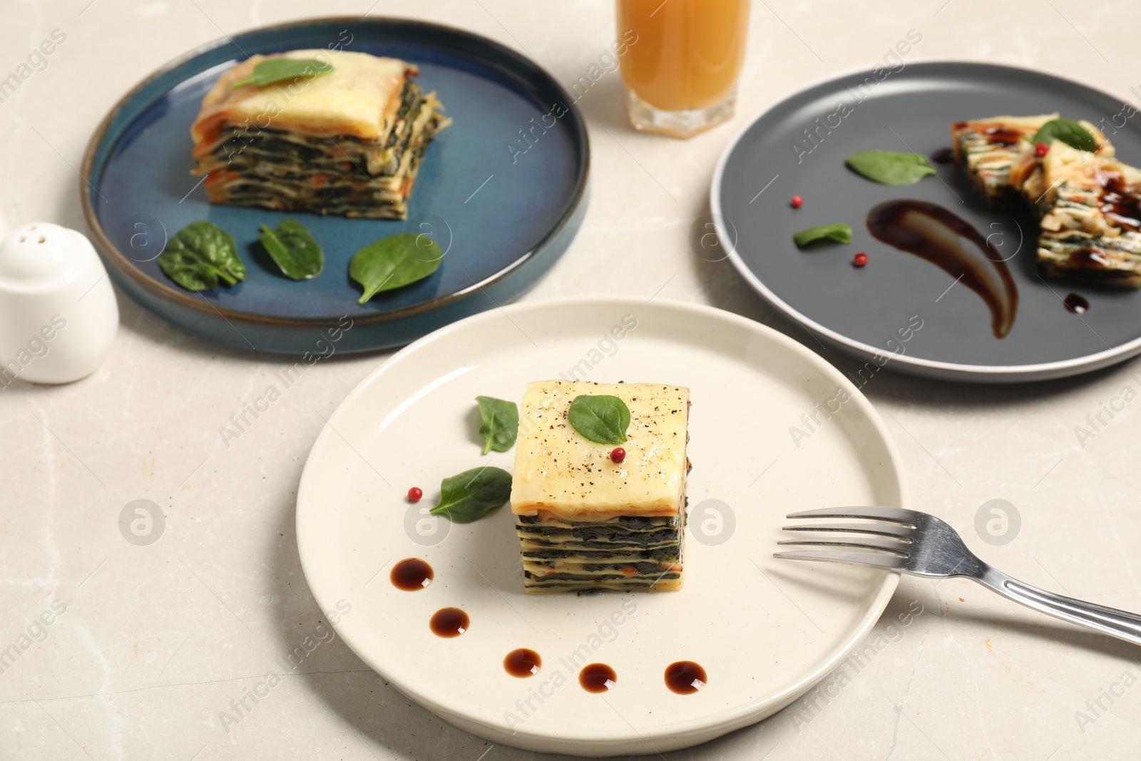 Photo of Pieces of tasty spinach lasagna on light marble table, closeup