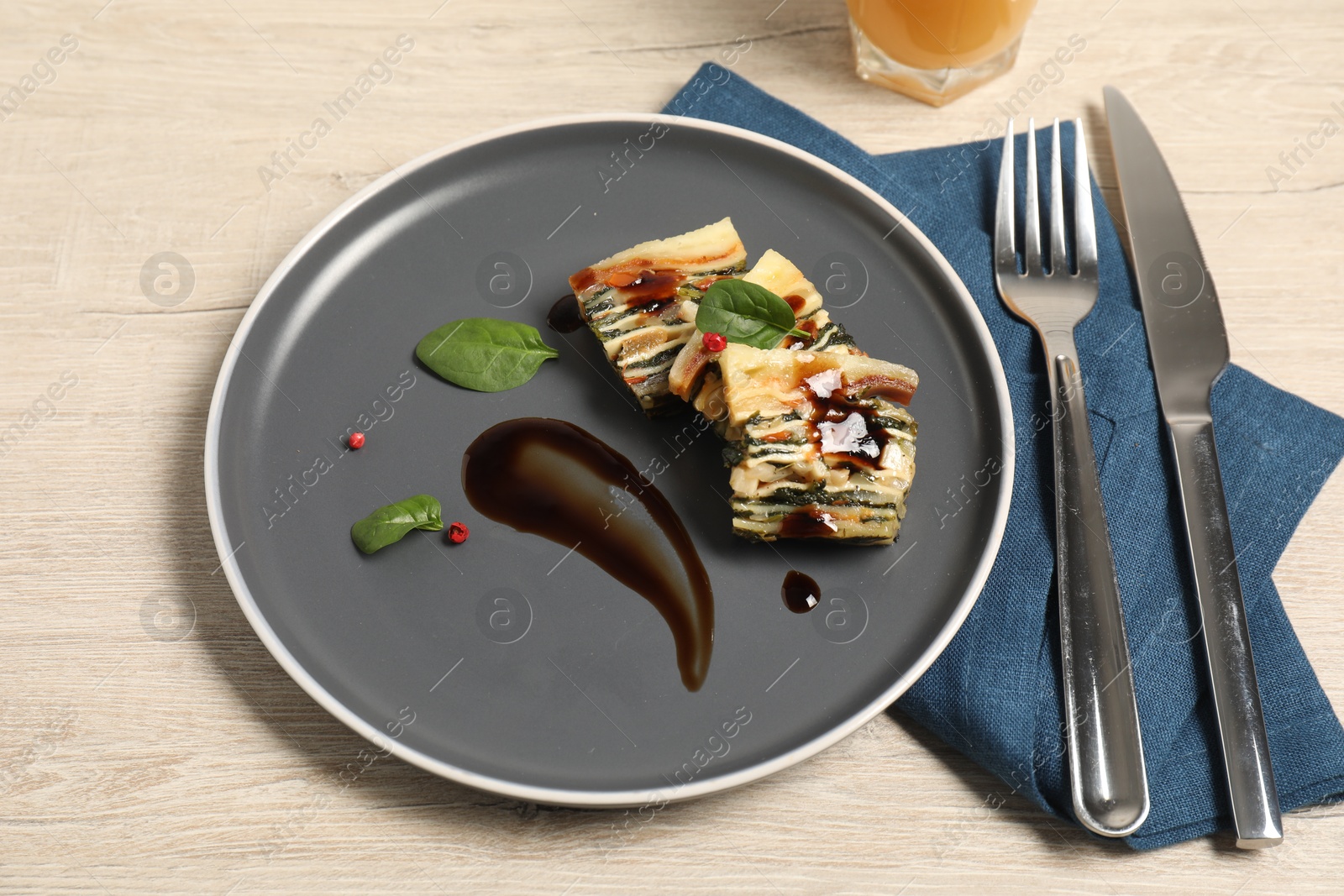 Photo of Pieces of tasty spinach lasagna served on wooden table, above view