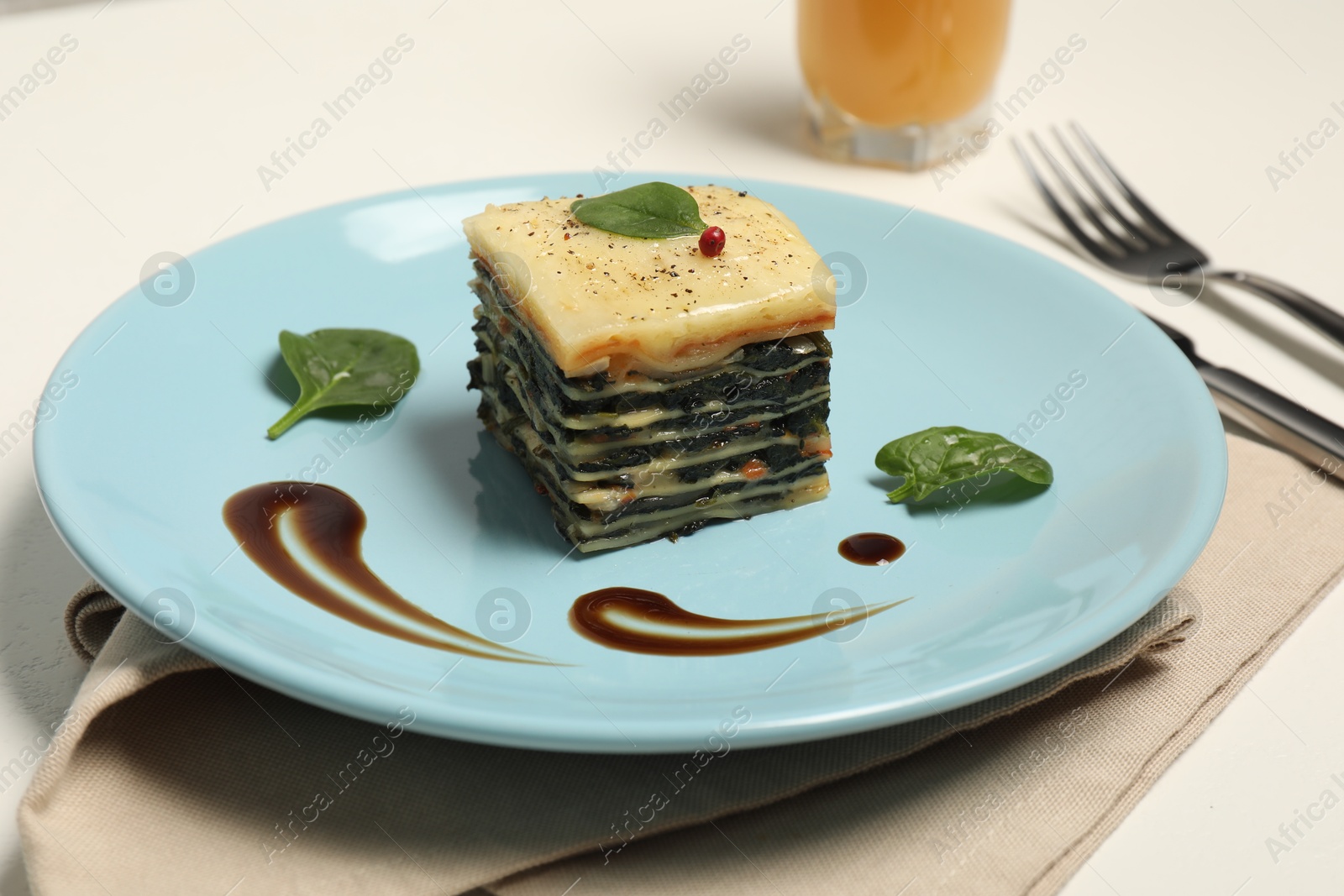 Photo of Piece of tasty spinach lasagna on white table, closeup