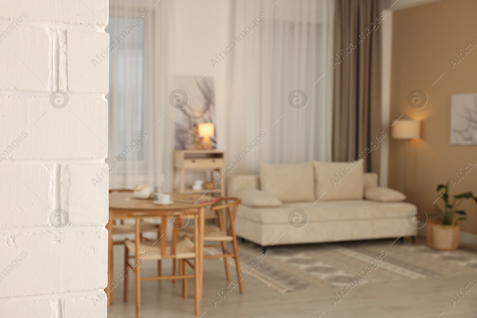 Photo of White brick column and furniture in cozy living room, selective focus. Interior design